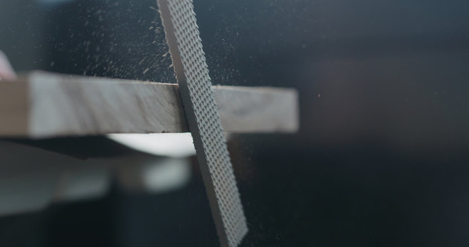 woodworker hand sanding walnut board with file