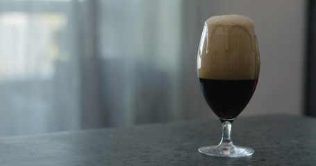 stout beer drops slide from tulip glass on terrazzo countertop with copy space