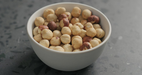 roasted hazelnuts in white bowl on terrazzo countertop