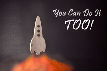 rocket takes off up against a dark background. tongues of flame are leveled below. concept of business, startup, success. the inscription on the right: "You can do it too!"