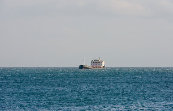 General cargo ship is in open sea in side sunlight.