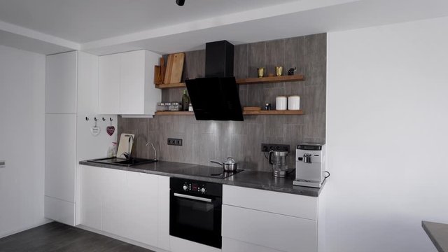 In the frame a modern, comfortable kitchen. Smart appliances are built into the minimalist interior. Natural materials in design.