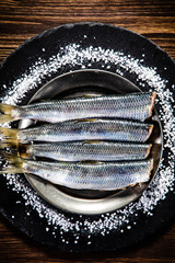 Fresh raw herrings on black stone board on wooden table