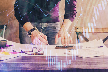 Multi exposure of man standing and planing investment with stock market forex chart.