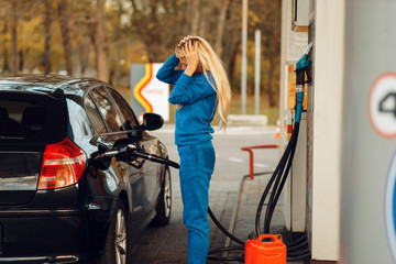Stressed woman on gas station, fuel filling