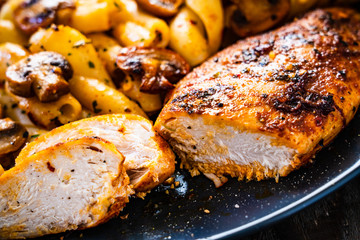 Roast chicken breast with pasta and vegetables on wooden background