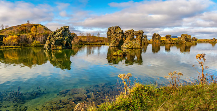 Amazing sunny day on lake Myvatn, Iceland, Europe. Volcanic rock formations reflected in the blue clear water of a volcanic lake. Artistic picture. Beauty world. Travel concept. Panorama