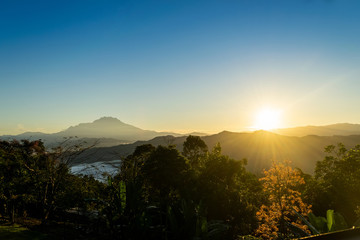 The mount Kinabalu with beautiful and mesmerizing sunrise, layers of foliages and hills shone by the rising sun.