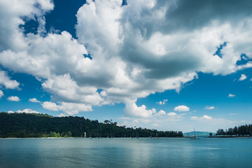 Panoramic view of blue cloudy sky, turquoise sea and mountain, Langkawi Island, Malaysia. Yachts anchored in calm waters of Strait of Malacca