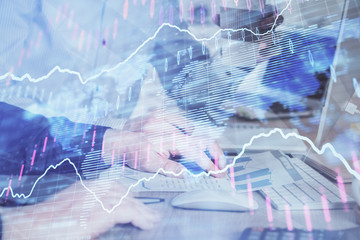 Multi exposure of chart with man typing on computer in office on background. Concept of hard work.