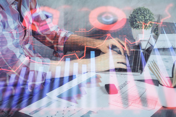 Double exposure of stock graph with businessman typing on computer in office on background. Concept...