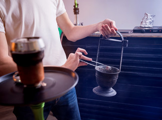 Cooking hookah in the bar. Young man with hookah in restaurant