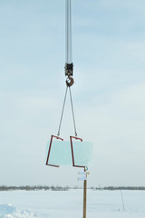 Truck crane lifts transparent ice slabs by the river