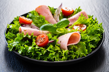 Tasty salad - ham and vegetables on black stone board