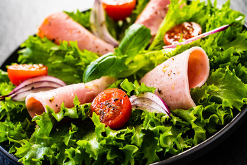 Tasty salad - ham and vegetables on black stone board