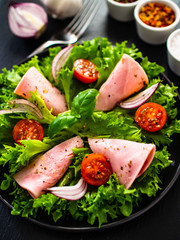 Tasty salad - ham and vegetables on black stone board