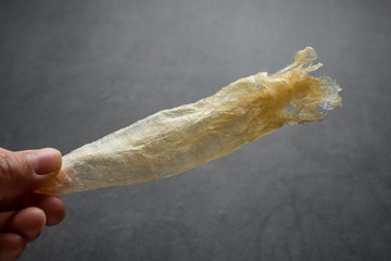 Hand holding golden yellow catfish glue on black background