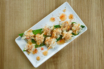 Traditional Chinese cuisine - Dim Sum with chicken, pork or seafood on a white ceramic plate with sweet and sour sauce on wooden background. Close up view