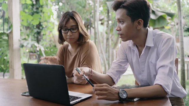 Two Young Indonesian Entepreneur working in the remote place, having a discussion looking at the laptop