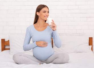 Joyful Pregnant Woman Drinking Milk Sitting In Bedroom