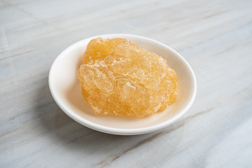 A dish of yellow rock sugar on the kitchen tile countertop