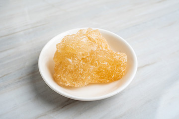 A dish of yellow rock sugar on the kitchen tile countertop