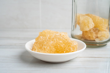 A dish of yellow rock sugar on the kitchen tile countertop
