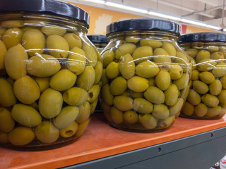 Gefüllte olivenbgläser im Regal