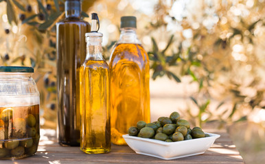 green olives and oil on table in olive grove