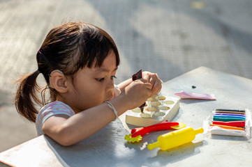 Hearing impaired children playing clay mold on the table in the park.