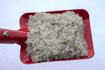 Rote Schaufel mit Streusalz vor dem Schnee