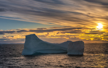 Goergeous sunset over giant icebergs and stunning polar landscapes along the coast of the Antarctic Peninsula