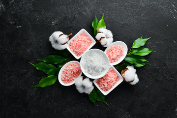 Cosmetic pink sea salt. On a black stone background. Spa treatments. Top view. Free space for your text.