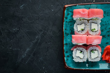 Sushi and rolls on the plate. Top view. Free space for your text. On a black background.