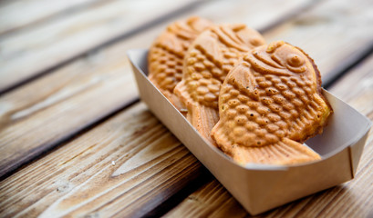 Taiyaki Japanese street food fish-shaped sweet filling waffle in box on wooden table