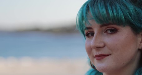Close-up of blue hair Gen Z woman looking alluringly at camera, copy space