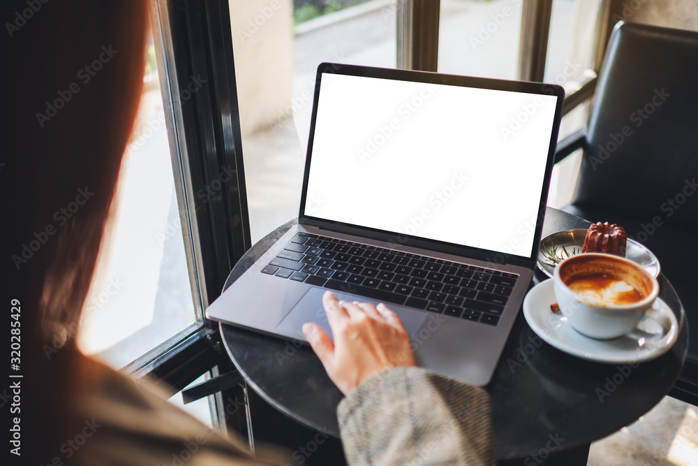 Wall mural mockup image of a woman using and touching on laptop computer touchpad with blank white desktop scre