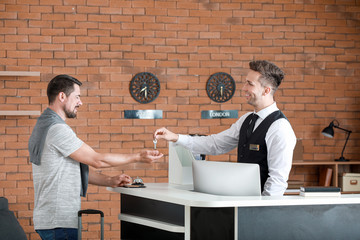 Man receiving keys from hotel room at reception