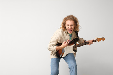 Emotional man playing guitar on light background