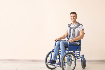 Handicapped young man in wheelchair near color wall