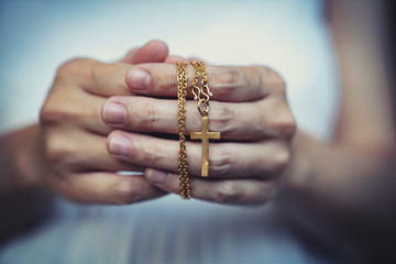woman hands praying holding a beads rosary with Jesus Christ in the cross or Crucifix on black...