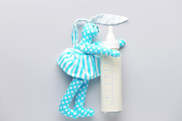 Bottle of milk for baby and toy on white background