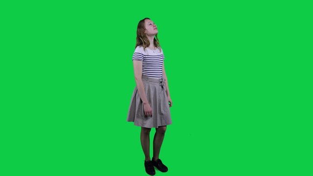 Side view teenage girl vibing to music in front of a green screen