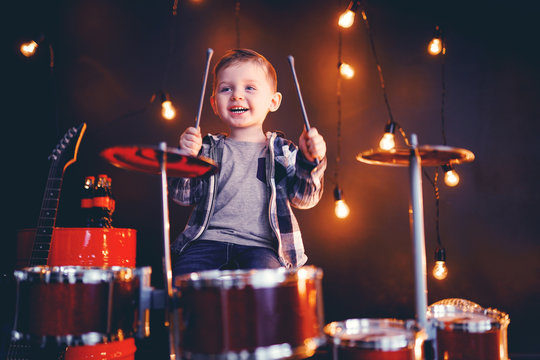 dark portrait of Beautiful boy playing the drums on a black background with smoke.
