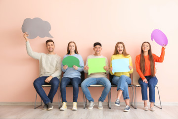 Fototapeta premium Group of young people with blank speech bubbles near color wall