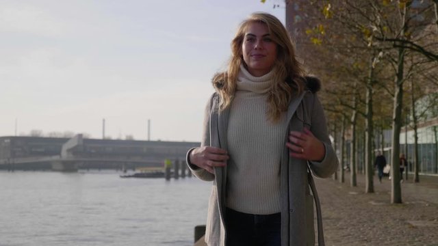 Confident Stylish Blonde Woman Struts Along The Pier In The Morning Sun. 