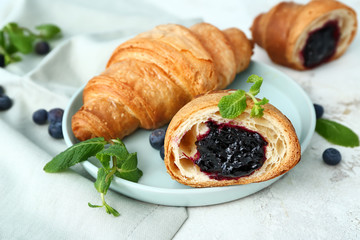 Plate with tasty sweet croissants on white background