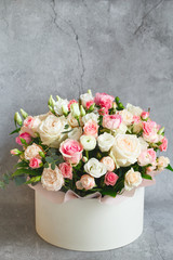Bouquet of beautiful flowers with peonies, roses and eustomas in the papper gift box in front of grey grunge background. Closeup picture. Valentine's Day. Mothers Day