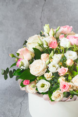 Bouquet of beautiful flowers with peonies, roses and eustomas in the papper gift box in front of grey grunge background. Closeup picture. Valentine's Day. Mothers Day
