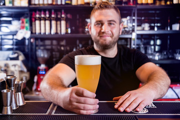 Bartender pouring draft beer at glasses in the bar. Restaurant.
